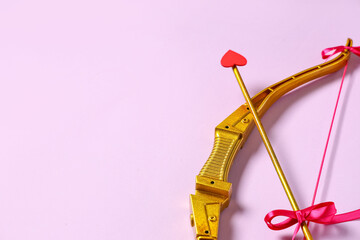 Naklejka premium Golden cupid's bow with arrow on lilac background. Valentine's Day celebration