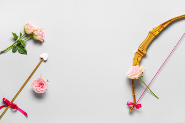 Naklejka premium Composition with cupid's bow, arrow and rose flowers on grey background. Valentine's Day celebration