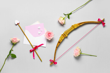 Naklejka premium Composition with cupid's bow, rose flowers, envelope and card on grey background. Valentine's Day celebration