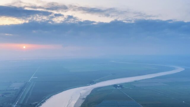 Aerial time-lapse of sunrise over the Wei River and Weihe Grand Bridge, serene dawn light, winding river, farmland, and vital transport infrastructure, Shaanxi Province, China.
