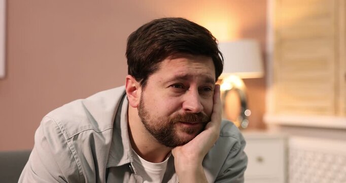 Unhappy man feeling fatigue on sofa at home. Camera moving forward