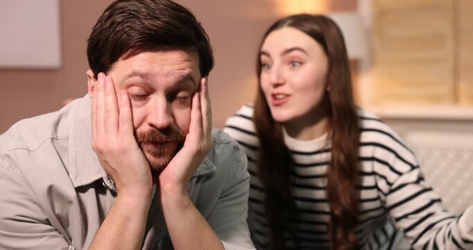 Embarrassed man ignoring woman on sofa at home. Camera moving forward