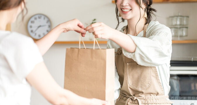 A female cafe attendant handing out takeout items to customers at a cafe or restaurant