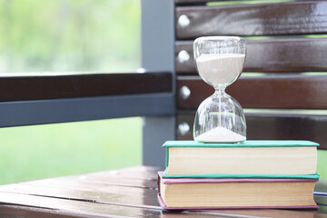 Hourglass with books on bench in park, outside