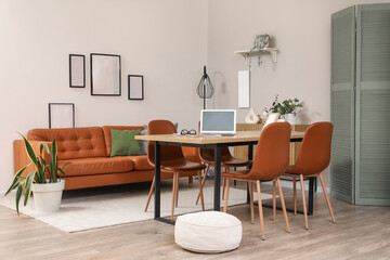 Interior of modern dining room with leather sofa, chairs, folding screen, commode and laptop on...