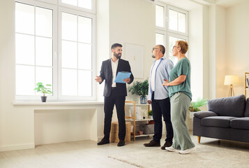 Realtor and agent guide a senior couple through new apartment during a tour and viewing, helping buyers assess the interior and showing key home features. Real estate market and buying property.
