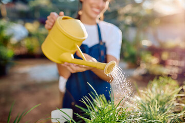 Smiling woman in an apron watering green plants with a yellow watering can, promoting plant care and sustainable growth © we.bond.creations