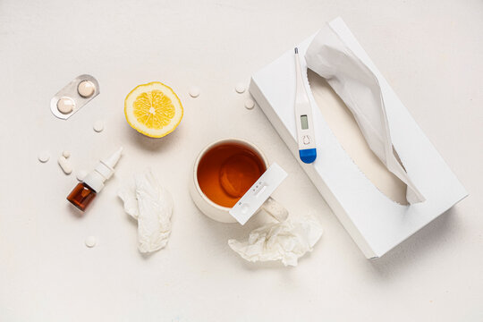 Rapid influenza test with cup of tea, thermometer, medications and tissues on white background