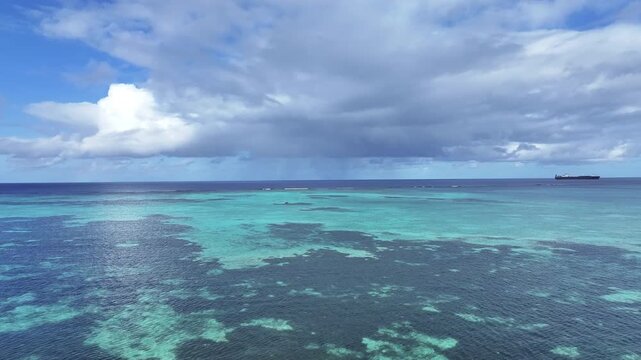 "A stunning aerial drone shot capturing the calm and crystal-clear emerald waters of Saipan&rsquo;s west coast. Features beautiful coral reefs visible through the transparent sea."