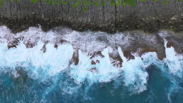 Witness the powerful convergence of history and nature. This dramatic drone footage captures the rugged northern coastline of Saipan, featuring the towering Banzai Cliff and Suicide Cliff. The deep bl