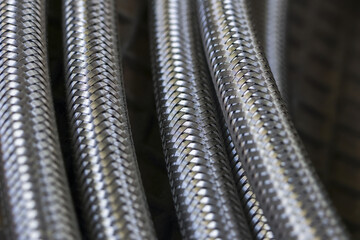 Close up view of flexible braided metal hoses, showing intricate steel texture and industrial pipe pattern. powerful image of durable connection and technology with blurred background