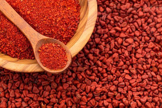 Organic red annatto seeds in spoon and bowl - Bixa Orellana