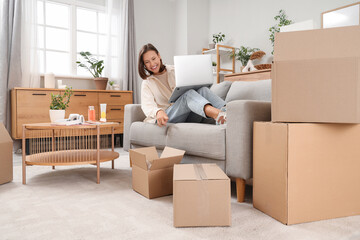 Fototapeta premium Beautiful young happy woman with laptop pointing at many parcels at home