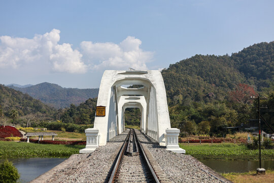 Scenic white railway bridge, beautiful travel destination in Thailand. This architecture provides peaceful view of green mountain landscape on clear day