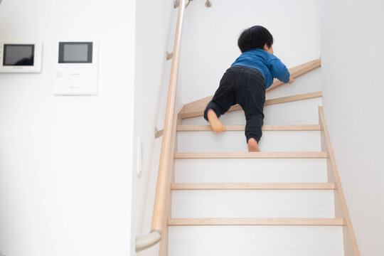ベビーゲートを越えて階段を上る幼児