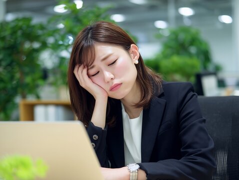 仕事中にデスクで眠気と疲労に悩むビジネスウーマンのオフィスシーン