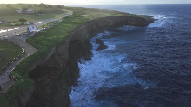 Witness the powerful convergence of history and nature. This dramatic drone footage captures the rugged northern coastline of Saipan, featuring the towering Banzai Cliff and Suicide Cliff. The deep bl