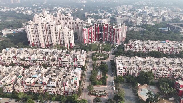 Aerial view of a planned residential township in Greater Noida featuring dense apartment complexes, symmetrical housing blocks, landscaped central greens, and high-rise towers in the background.