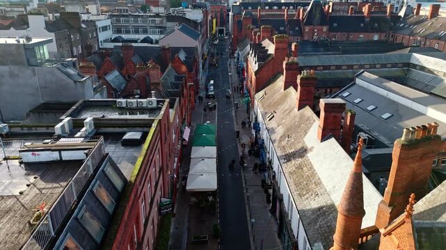aerial cinematic drone shot going down the capital of Ireland, Dublin's famous Drury street. With bustling roads and streets filled with tourists and locals alike with seagulls flying past at sunrise