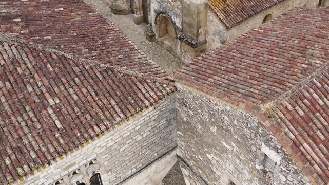 Aerial close-up showing texture of terracotta tiled roofs and ancient stone walls in the medieval bastide of Monpazier. Detailed view of historic architecture in the Dordogne region.
