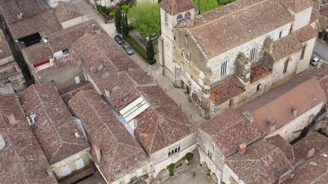 Drone footage overlooking the Saint-Dominique church and surrounding medieval houses in Monpazier. Scenic aerial view of historic bastide architecture and town layout in Dordogne France.