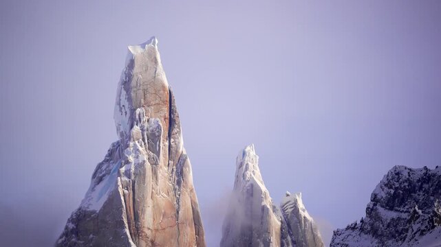 Moody view of Cerro Torre with twilight light and clouds wrapping the granite towers. Remote wilderness landscape in southern Patagonia.