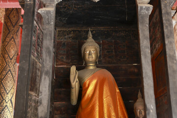 Obraz premium Serene golden Buddha statue inside an ancient wooden temple in Asia. This peaceful religious sculpture stands as historic symbol of faith, belief and worship