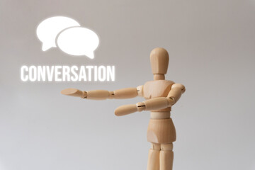 Wooden mannequin pointing to a speech bubble icon with the word "Conversation"