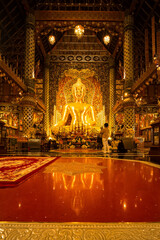 Obraz premium Chiang Mai, Thailand - January,08, 2026:Golden Shrine of Tranquility: The interior of a magnificent temple shimmers with ornate golden details, a large statue of buddha sits as the focal point