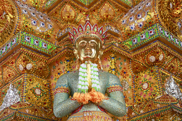 Obraz premium Serene green statue of deity at an ornate golden temple in Thailand. This spiritual asian sculpture shows traditional thai art, culture and ancient religious craft