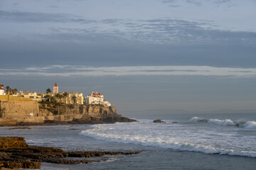 Surfer walking across rock jetty toward Atlantic Ocean