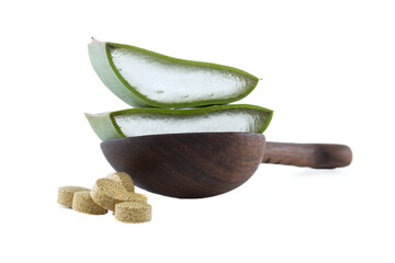Aloe vera slices and herbal supplements on a wooden spoon against a white background