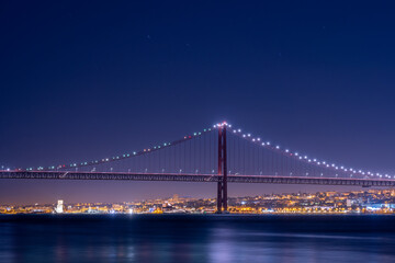 Obraz premium Lisbon waterfront with suspension bridge at night