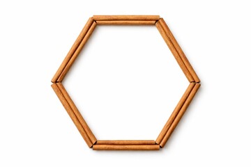 Cinnamon sticks arranged as geometric hexagon frame ends meeting with empty center copy space top view flat lay high key studio photo