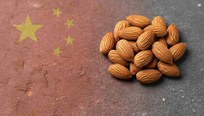 A heap of natural almonds rests beside the distinctive national flag of China on a rough surface.