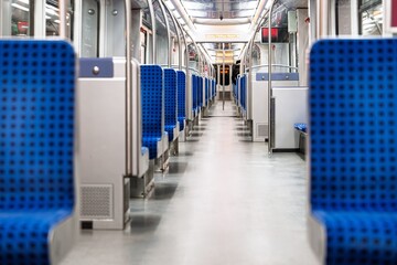 An interior view of an empty subway car, showcasing blue patterned seats. The scene evokes a sense of cleanliness and order, ideal for urban transport and commuting themes. © Ilja