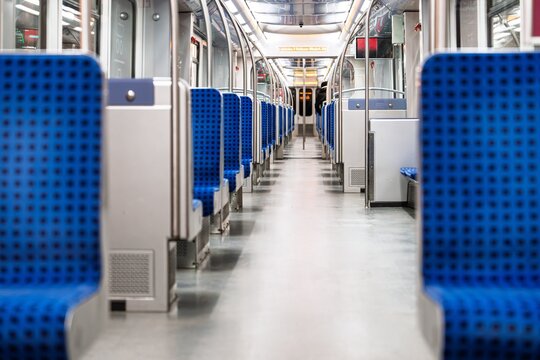 An interior view of an empty subway car, showcasing blue patterned seats. The scene evokes a sense of cleanliness and order, ideal for urban transport and commuting themes.