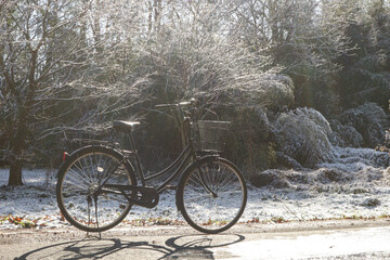 Obraz premium Black bicycle standing in a snowy landscape with trees in winter, cold season outdoor scene