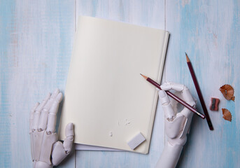 Top View of Robot Hands Holding Pencil Over Blank Notebook Page