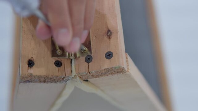 Carpenter installing a hinge with a screwdriver on wood