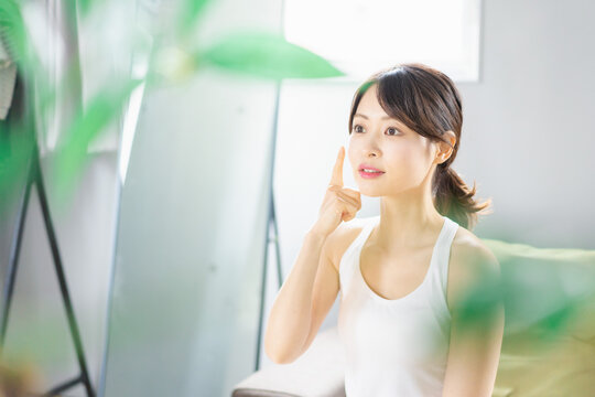 部屋でスキンケアをする若い女性