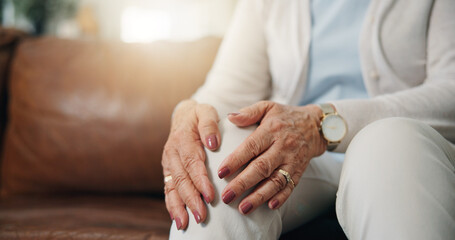 Hands, knee pain and senior person on sofa in living room of home for arthritis condition or symptoms. Joint, massage and space with elderly woman in apartment for fibromyalgia or osteoporosis