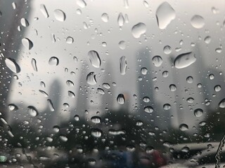 Raindrops on Window with Blurred City View. Raindrops on glass sharply contrast a soft-focus skyline of modern skyscrapers, capturing urban moodiness and rainy-day atmosphere.