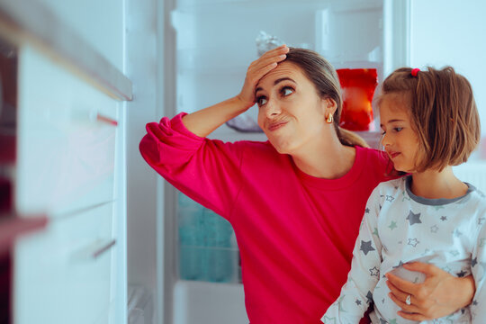 Little Girl and Mom Look in the Refrigerator and Find No Food. Daughter her mother Check the Refrigerator and Discover it is empty