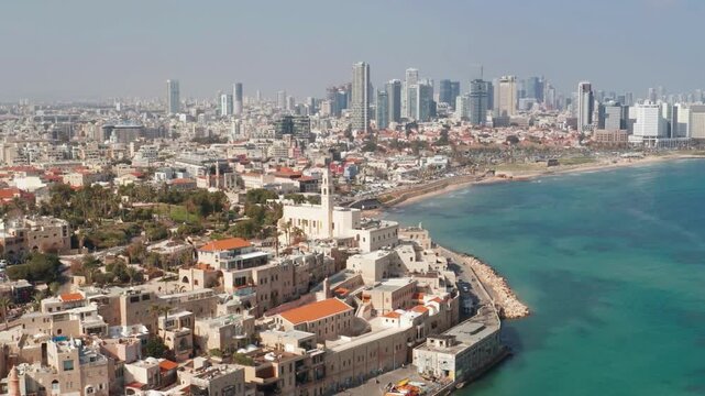 Tel Aviv skyline - Over the Mediterranean sea, Aerial footage. stunning aerial panoramic view of the historic Old Jaffa port and its limestone architecture overlooking the modern Tel Aviv skyline.