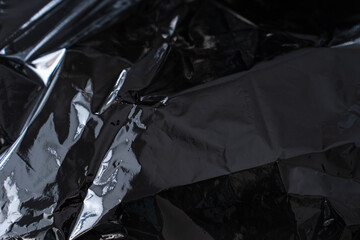 Crumpled dark metallic foil texture with sharp reflective folds