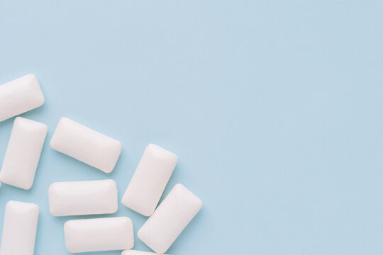 Scattered white chewing gum pieces on light blue background, minimal. High quality photo