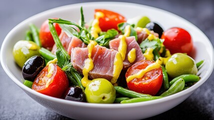 A vibrant salad nicoise elegantly assembled in a shallow white bowl, showcasing the bright colors of cherry tomatoes, green beans, black olives, and slices of fresh tuna. The dressing glistens under