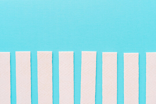 Row of chewing gum sticks on turquoise background, minimal flat lay. High quality photo
