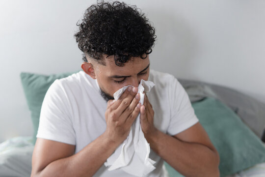 Sick man blowing nose suffering from flu symptoms